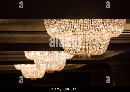 Große, kunstvoll verzierte Kronleuchter hängen von der Decke in einem teuren Hotel. Stockfoto