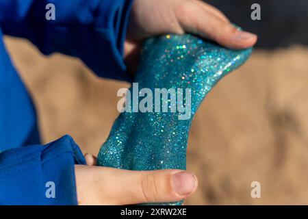 Eine Person hält ein grünes Objekt, wahrscheinlich Schleim, in der Hand. Stockfoto