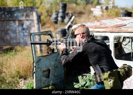 Ein Mann mit einem Maschinengewehr in der Hand macht eine militärische Ausbildung und lernt, auf den Schießstand zu schießen Stockfoto