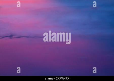 Die untergehende Sonne schafft ein abstraktes Pastellbild von Himmel und Wolken. Stockfoto