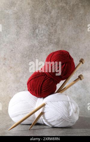 Zwei weiche Garnstränge und Stricknadeln auf grauem Hintergrund Stockfoto