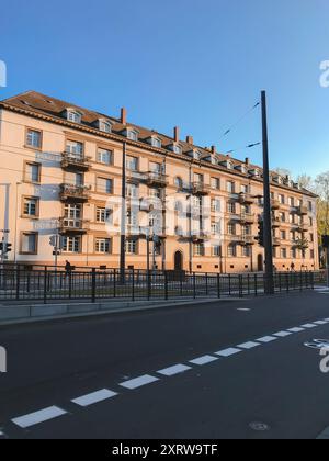 Ein großes Gebäude mit vielen Fenstern und Balkonen. Die Straße ist leer und der Himmel ist blau Stockfoto