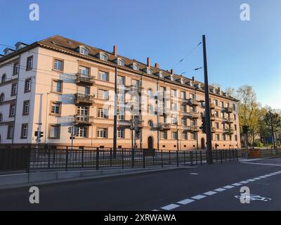 Ein großes Gebäude mit vielen Fenstern und Balkonen. Die Straße ist leer und der Himmel ist blau Stockfoto