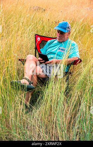 Allein erwachsener Mann im Ruhestand entspannt sich nach einem Tag des Kletterns und liest ein Buch über seinen Kindle. Blue Mountains, Oregon Stockfoto