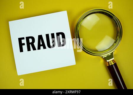 Betrugsnachricht auf Papiernotiz mit Vergrößerungsglas oben auf gelbem Hintergrund Stockfoto