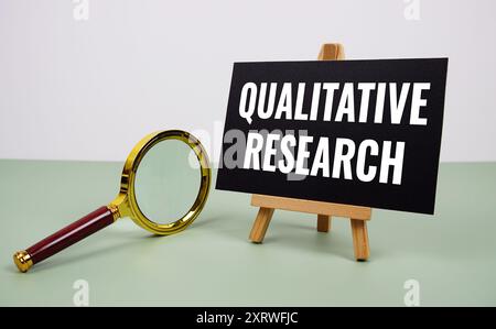 Qualitativer Forschungstext auf Papierkarte mit Lupe auf grünem Hintergrund Stockfoto