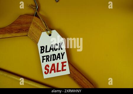 Black Friday Sale auf Preisschild mit hölzernem Kleiderbügel von oben auf gelbem Hintergrund Stockfoto