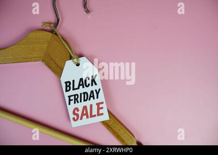 Black Friday Sale auf Preisschild mit hölzernem Kleiderbügel von oben auf rosa Hintergrund Stockfoto