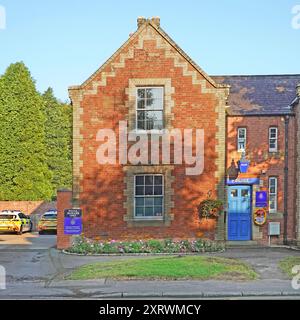 Bäume werfen Schatten auf altmodische Ziegelsteine gebaute traditionelle blaue Lampe Stadtpolizeistation mit Patrouillenautos außerhalb des Sedgefield County Durham England Großbritannien Stockfoto