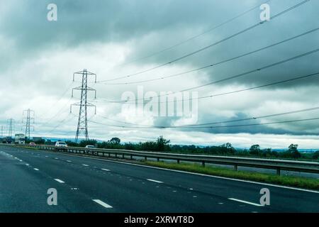 Freileitungen und Pylonen entlang der Strecke der Autobahn M6 in Cumbria. Stockfoto