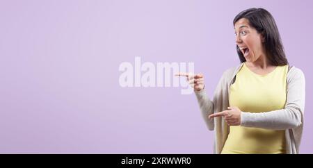 Aufgeregte Frau, die mit freudigem Ausdruck zur Seite zeigt Stockfoto