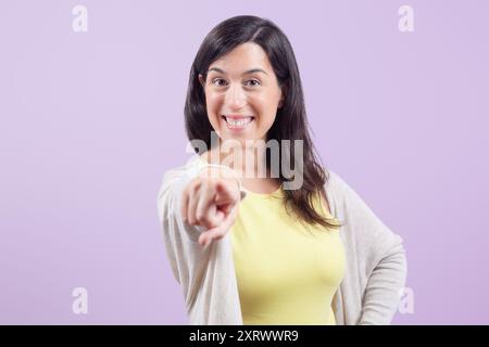 Eine Frau zeigt mit einem Lächeln auf die Kamera. Konzept der Positivität und Ermutigung, als ob die Frau hilfreiche Ratschläge oder Anweisungen gibt. Stockfoto