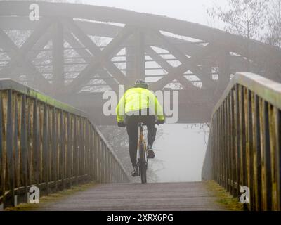 Ein landschaftlich reizvoller Teil der Themse, der in Kennington in den Hinksey Stream mündet. Dies ist Teil des Themsepfades und die Szene wird von zwei Brücken dominiert – einer verlassenen Eisenbahnbrücke, die viele Jahre ungenutzt war, in der Ferne; im Vordergrund eine Fußgängerbrücke über den Hinksey-Zufluss. Das Ergebnis ist eher abstrakt in der Komposition, besonders im Winternebel, bei dem ein Radfahrer die Fußgängerbrücke überquert. Stockfoto