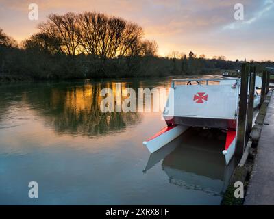 Das 1921 gegründete Radley Boathouse befindet sich an einem wunderschönen Teil der Themse in Oxfordshire und dient seit über einem Jahrhundert Radley College und lokalen Ruderfreunden. Hier sehen wir eine Reihe von Freizeitbooten, die an der Anlegestelle vor Anker liegen, während die Sonne aufgeht. Warum das maltesische Kreuz? Das ist eine lange Geschichte... Diese wurde ursprünglich vom College als Abzeichen für alle Sportarten um 1850 angenommen. Es wurde zum Symbol des Boat Club von der frühesten bekannten Crew und wurde wahrscheinlich zu Ehren von Sir George Bowyer, dem Besitzer von Radley Hall, adoptiert, von dem Haus und Gelände als Schule vermietet wurden Stockfoto