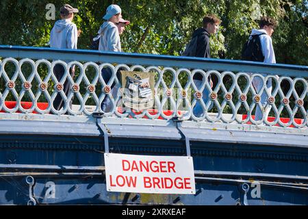 Osney Bridge, Oxford, bietet einige interessante Kontraste. Darunter liegt ein schöner ländlicher Abschnitt der Themse, der an dieser Stelle eher schmal ist; darüber summt die belebte Botley Road ständig mit Verkehr und - besonders im Sommer - Horden von Touristen. Beachten Sie das Wappen von Oxford auf der Brücke; auf der rechten Seite sehen Sie einen Ochsen, der den Fluss überquert (vordringt). So hat die Stadt ihren Namen bekommen, Leute - "Ox Ford". Einfach, oder? Stockfoto