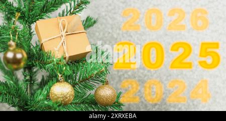 Happy New Year 2025 Jubiläum. Übergang von 2024 zu Neujahr 2025 Konzeptbild mit goldenem Kugelschmuck am Weihnachtsbaum. Stockfoto