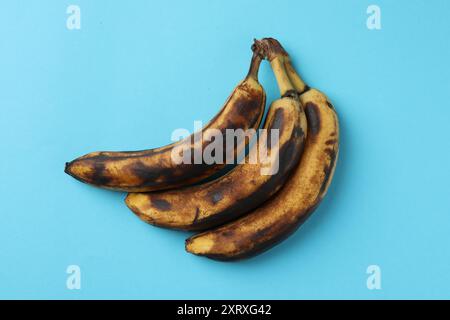 Ein Haufen reifer Bananen mit dunklen Flecken auf hellblauem Hintergrund, Draufsicht Stockfoto