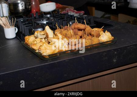 Gebratene Vorspeisen und gebackene Empanadas. Auf der linken Seite gibt es kleine goldene Backwaren, die anscheinend mit Käse oder Fleisch gefüllt sind. Auf der rechten ffa Stockfoto