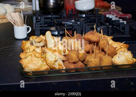 Gebratene Vorspeisen und gebackene Empanadas. Auf der linken Seite gibt es kleine goldene Backwaren, die anscheinend mit Käse oder Fleisch gefüllt sind. Auf der rechten ffa Stockfoto