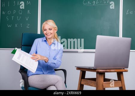 Foto von entzückender charmanter, cleverer Senior Frau, Universitätslehrerin, Lehrerin, Lehrstunde, erklärt Materialien der Grundschule Stockfoto