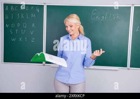 Foto einer hübschen, netten Dame, die als Lehrer das Thema des Unterrichts erklärt, isoliert auf grünem Bretthintergrund Stockfoto
