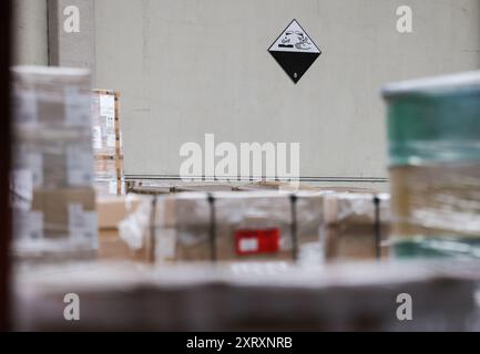 Hamburg, Deutschland. August 2024. An der Wand eines Lagers im Logistikzentrum DB Schenker der DCP Dettmer Container Packing GmbH im Hamburger Hafen hängt ein Warnschild „Dangerous Goods“. Quelle: Christian Charisius/dpa/Alamy Live News Stockfoto