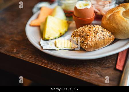 Kleines Paket Butter auf einem Frühstücksteller mit Brötchen Stockfoto