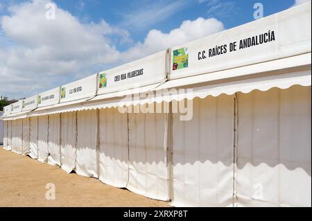 Viladecasn, SPANIEN - 12. AUGUST 2024: Messe Sant Isidro in Viladecans mit weißen Kabinen, Bäumen und Gebäuden im Hintergrund, unter teilweise bewölktem Ski Stockfoto