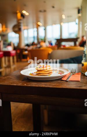 Köstlicher Stapel Pfannkuchen mit bunten Schokoladenlinsen und süßem Honig Stockfoto