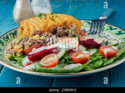 Cottage Pie mit Süßkartoffelbrei und Salat garniert mit Dressing. Stockfoto