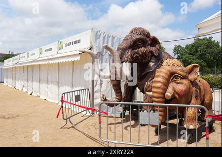 Viladecasn, SPANIEN - 12. AUGUST 2024: Mammut-Replikate auf der Messe Sant Isidro in Viladecans, mit weißen Zelten und teilweise bewölktem Himmel im Hintergrund Stockfoto