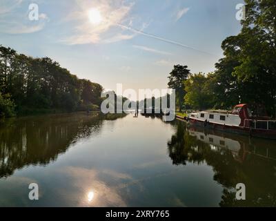 Blick auf die Themse vom Abingdon Lock. Abingdon-on-Thames behauptet, die älteste Stadt Englands zu sein. Und die Themse fließt durch ihr Herz. In dieser idyllischen Szene sehen wir von den Abingdon Locks aus einen recht schönen Blick auf den Fluss, gerade während die Sonne an einem schönen Sommermorgen aufgeht. So ruhig... Es gibt ein paar Aufnahmen, die es Wert sind, um 5:30 Uhr morgens aufzuwachen - aber dies ist sicher einer davon! Stockfoto