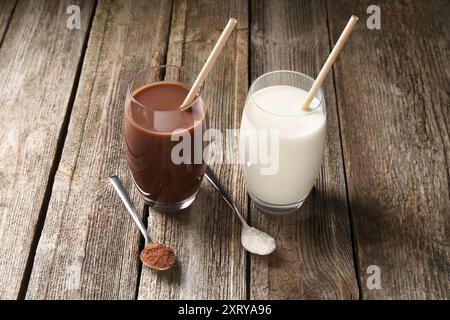 Köstliche Proteinshakes in Gläsern und Löffeln mit Pulver auf Holztisch Stockfoto