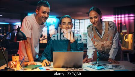 Posing-Aufnahme einer vielfältigen Gruppe talentierter junger Geschäftsleute, die sich um einen Schreibtisch in einem modernen Kreativbüro versammelten, um Brainstorming zu machen. Multiethnische Teamkollegen schauen in die Kamera und lächeln Stockfoto