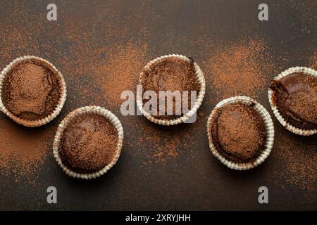 Schokolade und Kakao bräunliche Muffins von oben auf braunem rustikalem Steinhintergrund, süße hausgemachte Cupcakes aus dunkler Schokolade Stockfoto