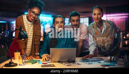 Posing-Aufnahme einer vielfältigen Gruppe talentierter junger Geschäftsleute, die sich um einen Schreibtisch in einem modernen Kreativbüro versammelten, um Brainstorming zu machen. Multiethnische Teamkollegen schauen in die Kamera und lächeln Stockfoto