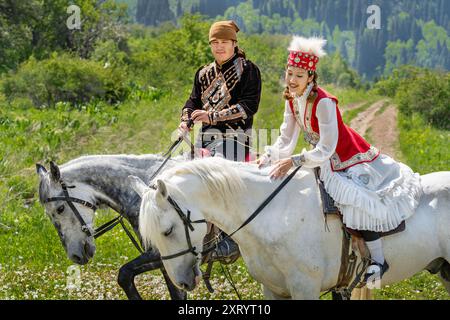 Nomadische Männer und Frauen in einheimischer Kleidung reiten in Almaty, Kasachstan. Stockfoto