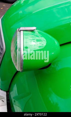 Klassische grüne Citroen 2CV mit Scheinwerferdetail vor einer Garage Paizay-le-SEC Frankreich Stockfoto