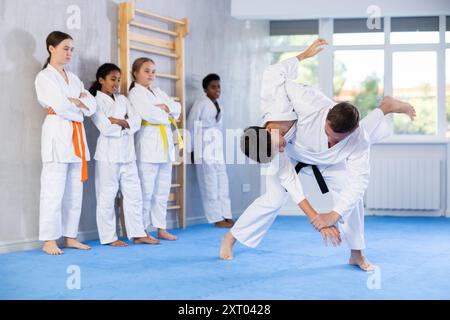 Judo-Trainer zeigt Kampftechniken im Sparring mit einem Jungen für eine Gruppe junger Athleten Stockfoto