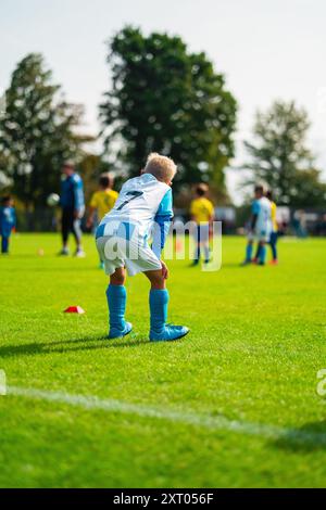 Junger Fußballspieler in weißem und blauem Trikot, der am Rande steht und darauf wartet, aktiviert zu werden Stockfoto