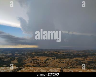 Sturmfront auf den sanften Hügeln: Ein Zusammenprall zwischen den Kräften der Natur. Dunkler Himmel über der sonnendurchfluteten Landschaft: Ein dramatischer Klimawandel. Kontrast Stockfoto