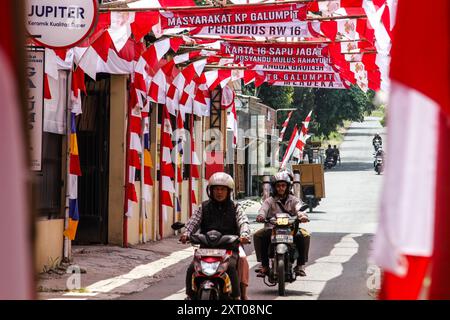 Bandung Regency, West Java, Indonesien. August 2024. Ein Motorradfahrer passiert eine Straße mit rot-weißen Verzierungen, die den 79. Unabhängigkeitstag der Republik Indonesien begrüßt, und 70 Meter rotes und weißes Tuch schmücken Cileunyi Kulon Village, Bandung Regency, West Java. (Kreditbild: © Dimas Rachmatsyah/Pacific Press via ZUMA Press Wire) NUR REDAKTIONELLE VERWENDUNG! Nicht für kommerzielle ZWECKE! Stockfoto