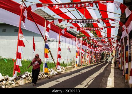 Bandung Regency, West Java, Indonesien. August 2024. Ein Bewohner passiert eine Straße mit rot-weißen Dekorationen, die den 79. Unabhängigkeitstag der Republik Indonesien begrüßt, und 70 Meter rotes und weißes Tuch schmücken Cileunyi Kulon Village, Bandung Regency, West Java. (Kreditbild: © Dimas Rachmatsyah/Pacific Press via ZUMA Press Wire) NUR REDAKTIONELLE VERWENDUNG! Nicht für kommerzielle ZWECKE! Stockfoto