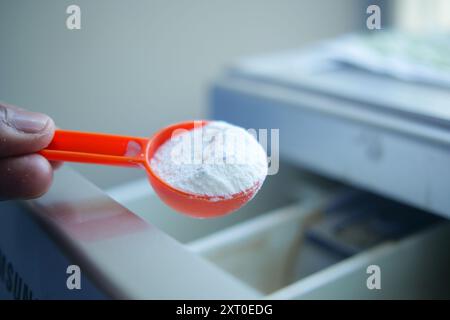 Gießen von Waschpulver in Kunststoffschale der Waschmaschine Stockfoto