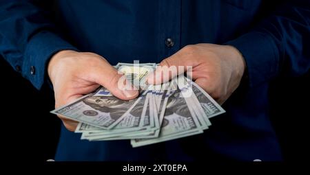 Ein großer Haufen Geld in der Hand. Nahaufnahme eines Geschäftsmannes zählt Geld in Händen. Us-Dollar Bargeld. 100-Dollar-Banknoten im Backgr Stockfoto