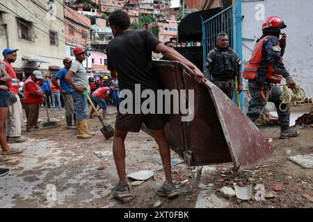 Caracas, Venezuela. August 2024. Ein junger Mann trägt eine beschädigte Tür nach einer Explosion im Stadtteil La Unión de Petare im Bundesstaat Miranda, östlich von Caracas. In Venezuela gab es mehrere Opfer nach einer Gasexplosion in einem Wohnhaus. Quelle: Jesus Vargas/dpa/Alamy Live News Stockfoto