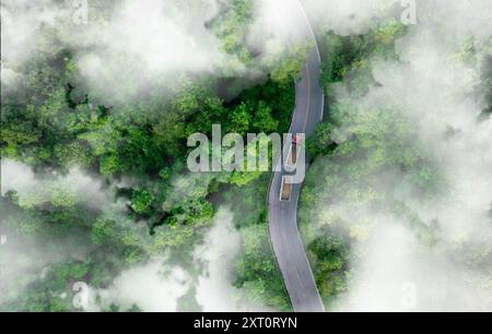 Luftaufnahme eines Wasserstoffkraftwagens auf Autobahnstraßen im grünen Wald. Nachhaltiger Transport. Blauer Lkw fährt auf Asphaltstraße im Wald Stockfoto