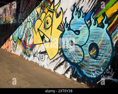 Kontraste. Dieses Bild von Graffiti an der Themse in der Nähe von Oxford zeigt nicht den Verkehr, der Tag und Nacht auf der Brücke vorbeifließt und den verstopften Eastern Bypass über den Fluss trägt. Die Schatten passen auf den ersten Blick ziemlich gut zum Kunstwerk Optik in Aktion... Stockfoto