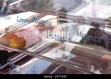 Zitrone, Brombeere, Bubblegum handgeschriebene Typografie verschiedener Macaron-Aromen auf Glas mit Reflexion von lokalen Bäckerverkäufern am Trout Lake B Stockfoto