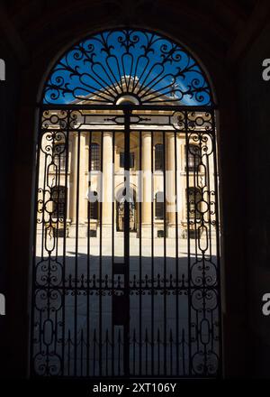 Das Clarendon Building ist ein neoklassizistisches Gebäude aus dem frühen 18. Jahrhundert der University of Oxford. Es befindet sich in der Broad Street, neben der Bodleian Library und dem Sheldonian Theatre und in der Nähe des Stadtzentrums. Hier sehen wir die Fassade, die von den geschlossenen Toren eingerahmt wird, die zur Bodleian Library führen. Stockfoto